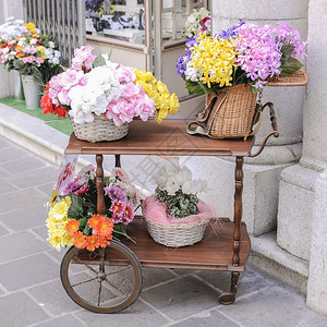 轮子目的一辆配有过压篮子的马车和一个装满鲜花供出售的老鱼叉篮子正方形图片