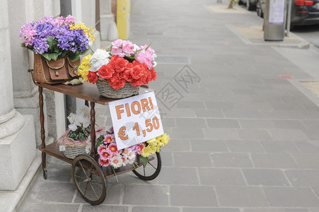 一辆配有过压篮子的马车和一个装满鲜花供出售的老鱼叉篮子外部的优质目图片