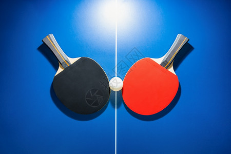 冠军两桌网球板是室内运动的体育竞赛设备彩色和红桌网球拍打红色桌黑网蓝乒乓在色桌上有明亮的聚光灯两桌网球掌是室内运动的竞技设备蓝色图片