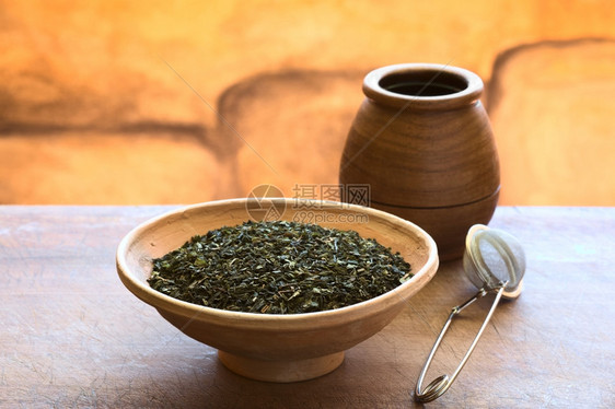 药用晒干喝茶叶的三分之一是选择焦点重为茶叶的三分之一在茶叶中以自然灯光拍照时用茶叶中的3分1之一淡绿色茶叶和木杯拍摄图片