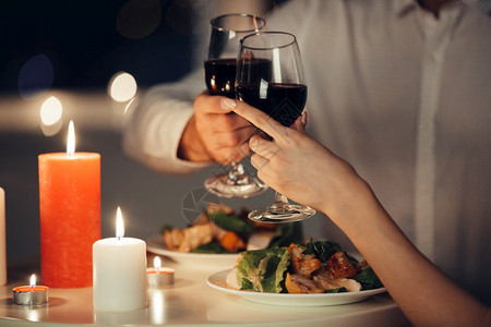 庆祝葡萄酒晚上年轻情侣在家里吃浪漫晚餐和喝红酒的剪裁照片情人在家吃浪漫晚饭的剪裁照片在图片