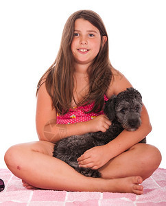 宠物快乐的白种人穿着泳衣的黑发笑脸少女在海滩上游泳衣的女孩与她小船狗工作室设置成粉色毛巾图片