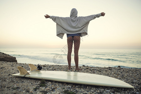 海滩上享受落日的女冲浪者背影图片