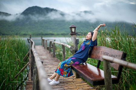 夏天海滩景观坐在码头上的女人看着日落的美丽图片