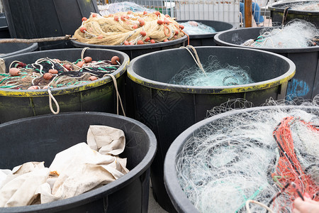 在意大利古里亚瓦拉泽港口码头的捕鱼日之后在西滨的大型塑料桶内安装渔网海港岸线象征图片