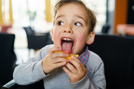 孩子们柑橘坐在椅上舔一小片柠檬刺舌头做面孔的三岁幼小白人男孩的肖像他们坐在椅子上吃图片