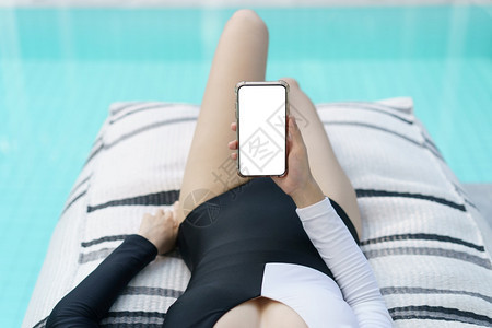 泳装女子在游池看手机屏幕图片
