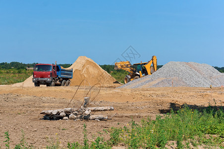 下一个堆沙子旁边的卡车和挖掘机采石场砂一堆沙子旁边的卡车和挖掘机装载桩图片