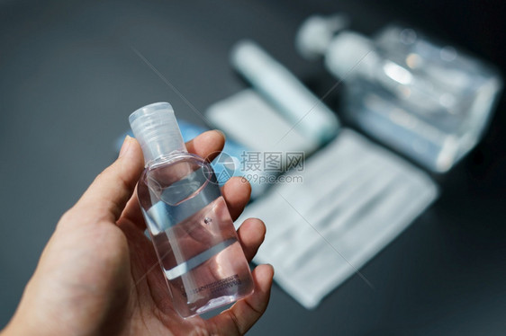 瓶子消毒与装酒精凝胶和面罩一起放在桌上流行病期间必须携带物品外科图片