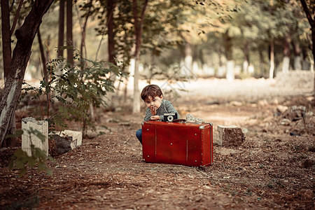 可爱小男孩拿着旧式手提箱背景图片