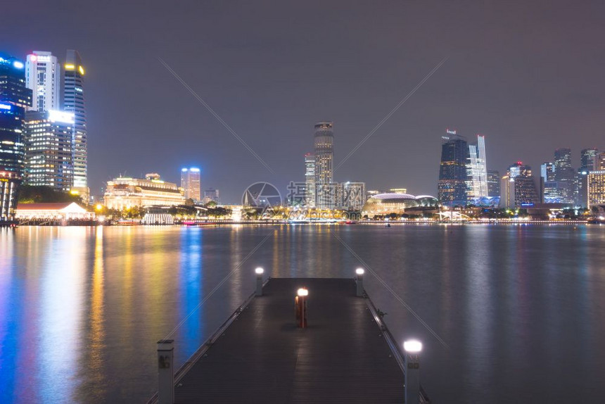 河日出新加坡市的摩天大楼夜幕后背景商业大楼位于新加坡城深夜湖图片