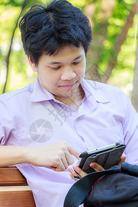 当代的个人电脑穿紫色衬衫的年轻人在公园里拿着平板电脑男图片