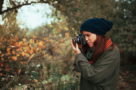 户外年轻女子用旧的模拟相机在森林里拍照远足人们图片