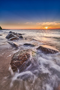 海边击打岩石的浪花与夕阳图片