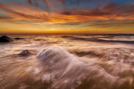 海边击打岩石的浪花与夕阳图片