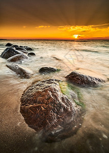 海边击打岩石的浪花与夕阳图片