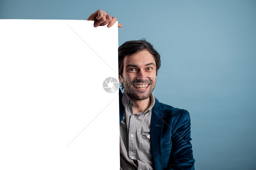 常设快乐的男人拿着一张白色的海报快乐微笑年轻人展示空白招牌与的复制间区域用于标语或广告短信概念中的白种人男模特保持木板图片