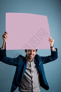 男快乐的人拿着粉红色的海报快乐微笑年轻人展示空白招牌与的复制间区域用于标语或广告短信概念中的白种人男模海报快乐标语牌图片