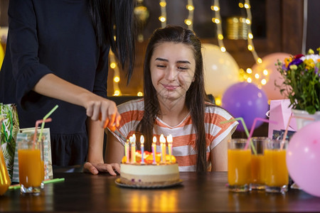 快乐的少女和母亲生日晚会上蛋糕在上点燃蜡烛喝灯光家图片