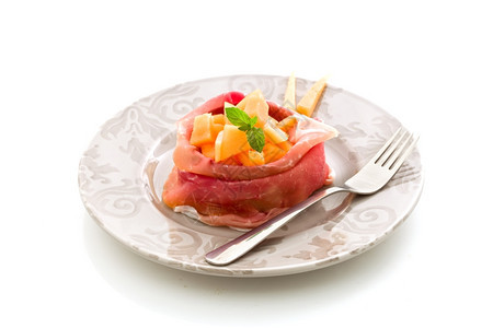 沙拉快速地帕尔马以白色孤立背景的西红柿和甜瓜拍摄了一幅美味切片培根的照图片