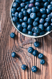 食物将新收集的蓝莓放入陶瓷碗中一些水果自由散布在旧木板桌上从到下成熟有机的图片