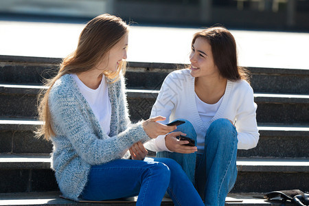 高加索秋天两位快乐的女青少年在街上一起聊天坐在楼梯上Stairs人们图片