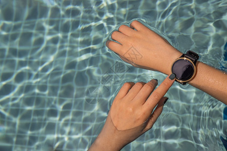 使用智能手表在游泳池用智能手表亲近女健康生活方式概念电子的无线监视器图片