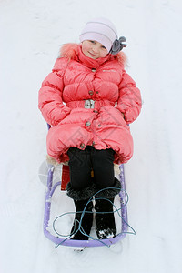 松弛生活坐在红色羽毛床上的雪橇漂亮女孩新图片