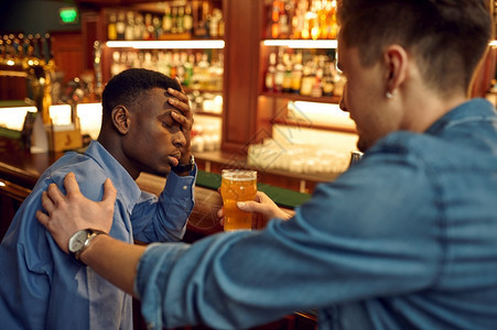 派对夜生活两个男朋友在酒吧的柜台喝啤人们在吧放松夜间生活方式友谊动庆祝男朋友在酒吧的柜台喝啤俱乐部图片