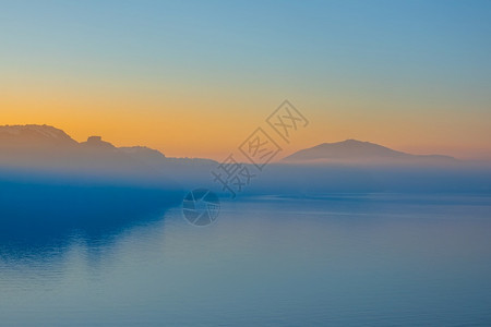 天际线在圣托里尼海边和岩石岸背景下的清晨雾中桑托里尼岛无云日出黄昏火山图片
