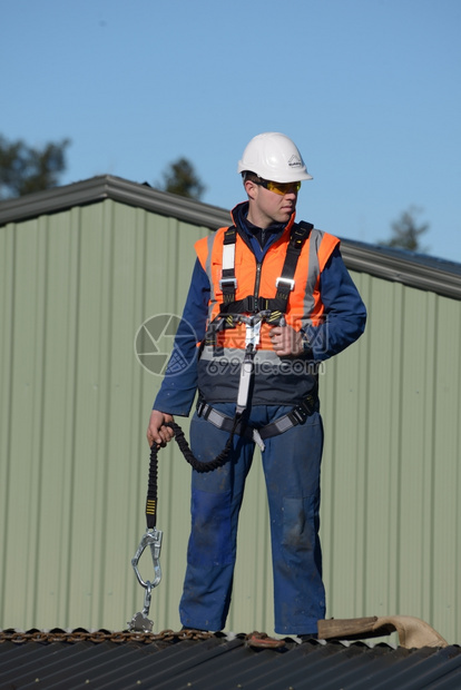 交易建筑工在高山作时身着安全带等待工头的指示在高山工作时身着安全帽的建筑工屋面团队图片