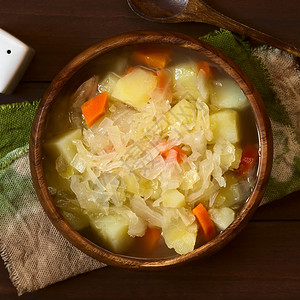 拍照素食主义者乡村以土豆和胡萝卜做成木碗用自然光照黑木头上方的浅色淡紫聚焦点重在盘子顶端有选择的焦点放在盘子顶端图片