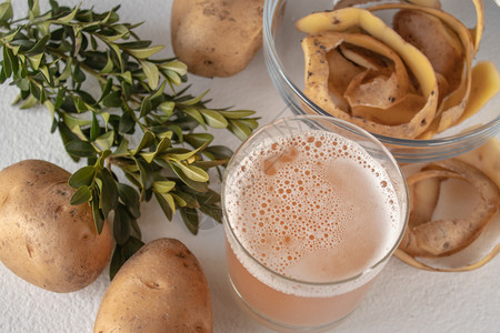 小吃饮食甜的玻璃杯中果汁和土豆在白色背景上从面看果汁在玻璃杯中和土豆图片