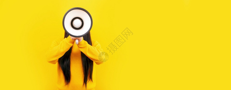 穿着黄色毛衣的女孩用黄背景的扩音器丰富多彩的公告吸引人图片