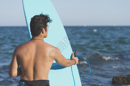 男人拿着冲浪板望向大海图片