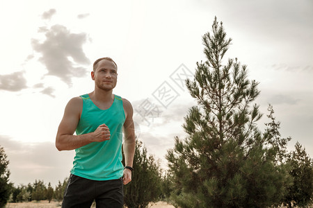 运动慢跑者穿着蓝色T恤和黑短裤的白人男子日落时穿梭粗野地形训练嬉戏的图片