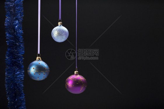 黑背景上挂着多彩的圣诞节球黑背景上挂着三个多彩的圣诞节球新明亮复制空间图片