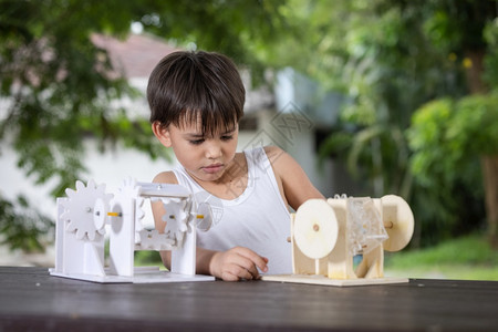 有创造力的教育一个男孩子注意学习模拟机制在家里桌上的木制机器人模型板机设计师图片
