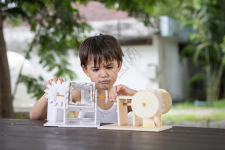 一个男孩子注意学习模拟机制在家里桌上的木制机器人模型板机一种工程师图片