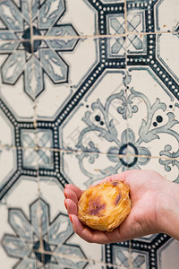 小吃巴斯德在葡萄牙里本的Azulejo背景介绍中葡萄牙传统的妇女手持葡萄牙传统鸡蛋煎糊饼糕甜点阿苏莱霍斯图片