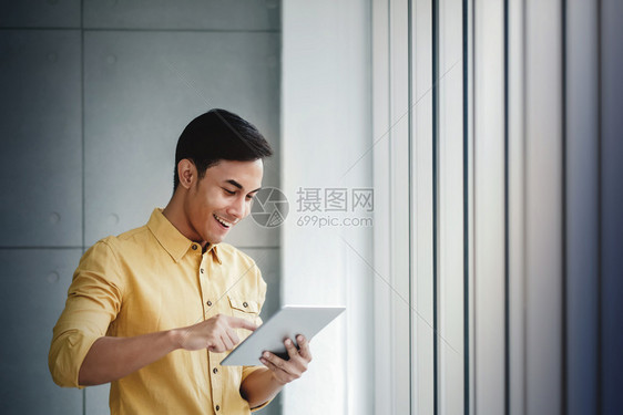 利用数字板块和微笑办公室的窗口站立在使用数字板和微笑的窗口旁经过在线的打算图片