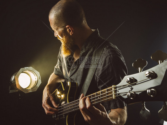 音乐家艺术照片中一位留胡子男在聚光灯前的舞台上玩电吉他潮人图片