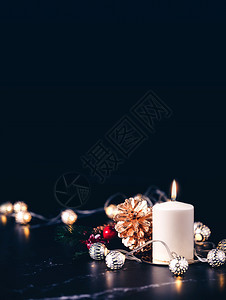 圣诞白蜡烛配有金松锥米斯利诺和光线绳在黑色大理石桌上闪耀面带深底脊横旗的黑色背景贺卡传统的垂直银图片