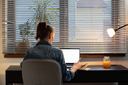 在黄昏白屏计算机上工作的妇女在复印空间的白色屏幕上工作的营销数字图片