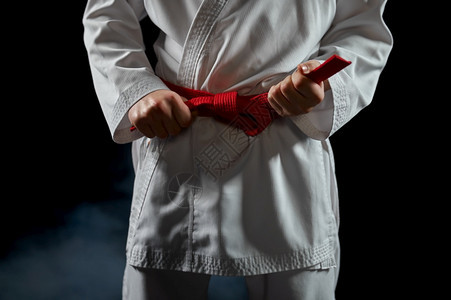 冲床白和服的男空手道斗士有红带战姿势黑暗背景的空手道运动武术在比赛前训练白和服的拳手有红腰掌握强的图片
