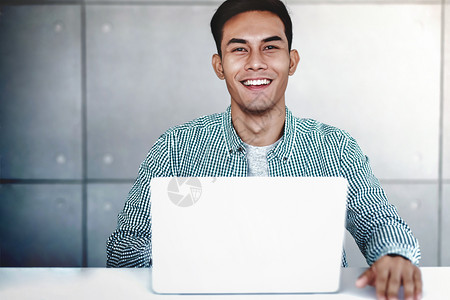 复制技术聪明的亚洲青年商业家在办公室微笑和看相机电脑笔记本上工作肖像图片