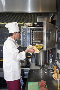 油一位厨师将盘土豆放入专业烤箱单身的厨房图片