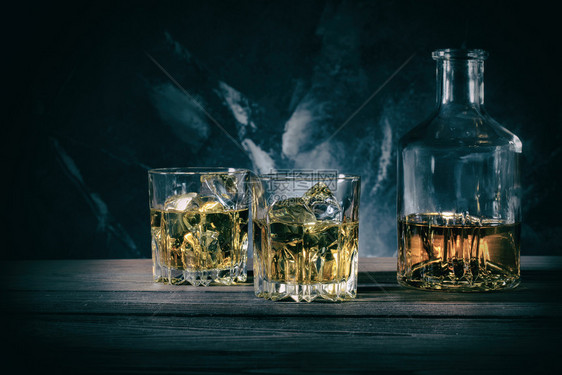 苏格兰人醒酒器和两杯深色大理石背景加冰的威士忌ToningDecanter和大理石背景上的两杯威士忌科涅克白兰地复制空间图片