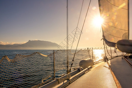 船轨在阳光明媚的天气下在海上游艇航行护帆站在一艘游艇的甲板上闪耀太阳背面海景图片