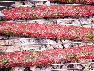 周末炙烤温暖的肉串在热木炭烧烤上的特写图片